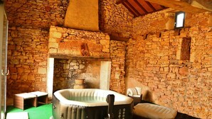 Ein Zimmer mit Steinwänden, einem Kamin aus Stein, einer Whirlwanne und einem an der Wand montierten Fernseher.