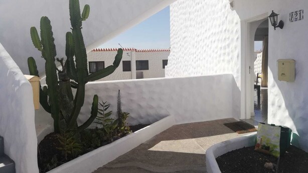 A white building with a large cactus in a planter, a door labeled "A21", and a small garden area. - Beautiful apartment to feel good and relax (Costa Calma)
