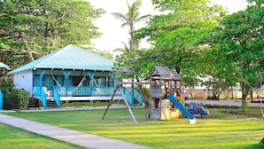A house with a blue roof and a small playhouse with a slide. - Arenas Beach Hotel (Corn Islands)