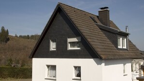 Una casa a due piani con un tetto ripido, pareti esterne bianche e numerose finestre.