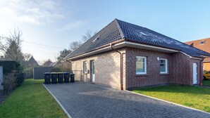 A single-story brick house with a tiled roof, a paved driveway, and a fenced yard. - Vacation home Lucky with pet (Norden)