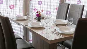 A dining table set with plates, glasses, and cutlery, surrounded by chairs. - Vacation home Lucky with pet (Norden)