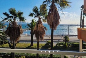 A balcony with a view of the sea, palm trees, and a promenade. - Magnificent air-conditioned apartment, sea view, elevator, Internet, Parking (Cavalaire-Sur-Mer)