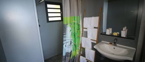 A bathroom with a shower curtain, a sink, a mirror, and a towel rack.