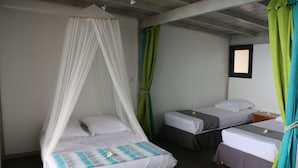 Une chambre avec deux lits simples, dont l’un est doté d’un baldaquin et l’autre non. Il y a une petite fenêtre sur le mur, et la chambre a un plancher en bois.
