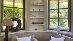 Une pièce chaleureuse avec une grande fenêtre, une guirlande décorative, une lampe et une étagère sur laquelle sont disposés divers objets.