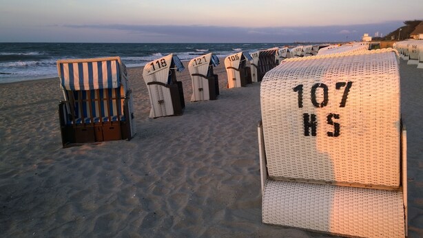 Strandliegen mit Nummern, auf dem Sandstrand in der Nähe des Ozeans aufgestellt.