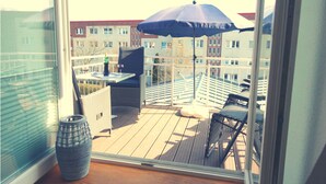 Ein Balkon mit Tisch, Stühlen und einem blauen Sonnenschirm.