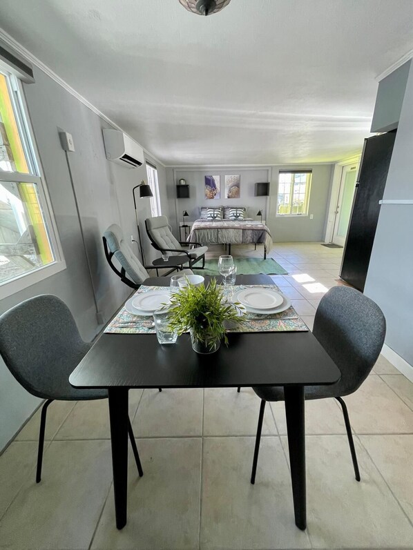 Un coin repas avec une table dressée pour quatre personnes, un canapé et un lit en arrière-plan.