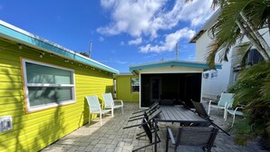 A patio area with a table and chairs, a covered seating area, and a building with a green exterior. - Sun, beach, and great deals—discover dream vacation destinations with discounts (Matlacha)