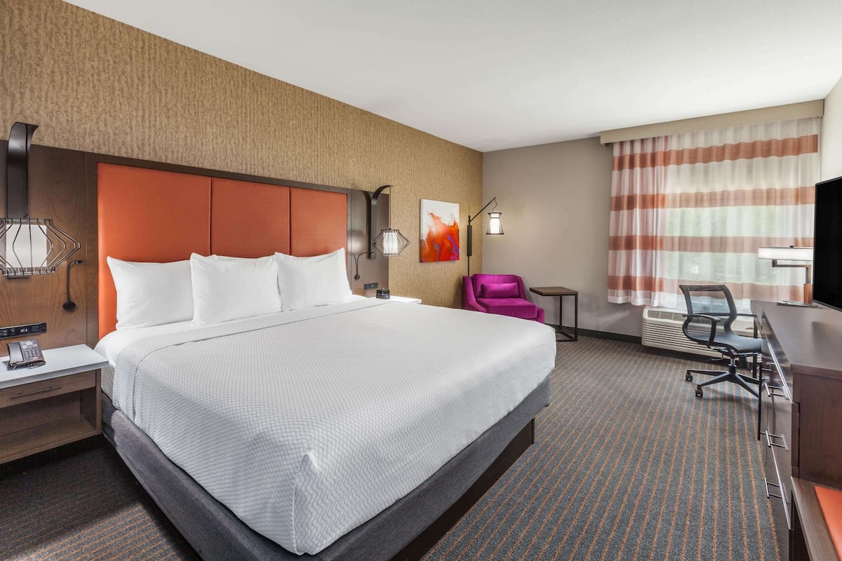 Een hotelkamer met een groot bed, een bureau, een stoel, een telefoon en een televisie.