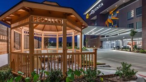 A hotel entrance with a covered outdoor seating area and a modern building facade.
