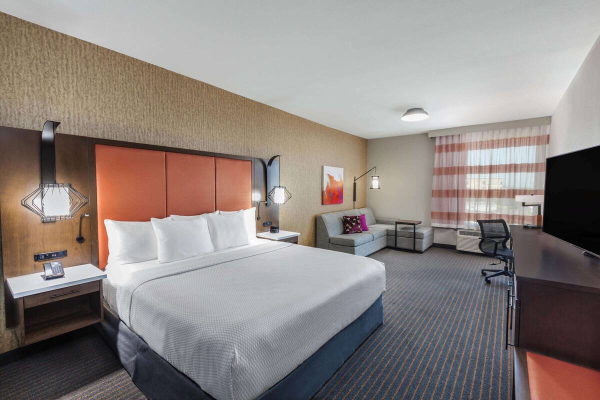 Een hotelkamer met een groot bed, een bureau, een stoel, een bank en een televisie.