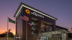 A modern hotel with a prominent "La Quinta" sign, multiple floors, and a covered entrance.
