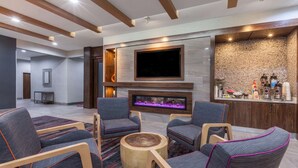 A modern living area with a flat-screen TV, a fireplace, and a bar area with various bottles.