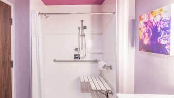 A modern bathroom with a walk-in shower, a grab bar, and a white sink.