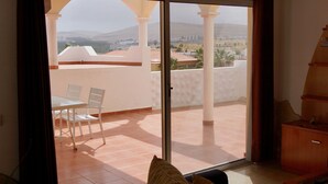 A room with a sliding glass door leading to a balcony with a tiled floor and a table with chairs. - Spacious house with 3 bedrooms, 2 bathrooms, swimming pool (Costa Calma)