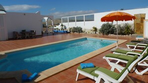 A swimming pool with lounge chairs and an umbrella. - Spacious house with 3 bedrooms, 2 bathrooms, swimming pool (Costa Calma)
