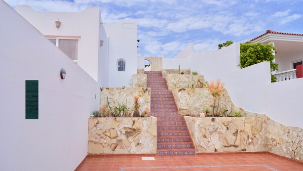 A staircase leading up to a building with white walls and a stone wall with a patterned design. - Spacious house with 3 bedrooms, 2 bathrooms, swimming pool (Costa Calma)