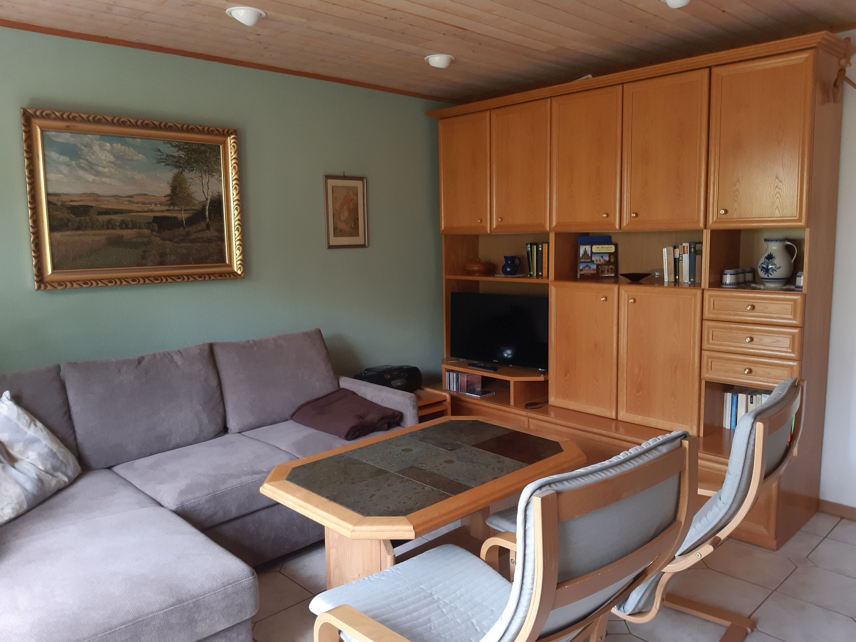 Un salon avec un canapé, un téléviseur, des meubles en bois et une table.