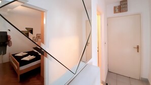 Ein modernes Interieur mit einer Treppe, einem Bett mit ordentlich gefalteten Handtüchern und einer Tür mit Lichtschalter.