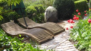 A garden with a paved walkway, wooden lounge chairs, and red tulips. - Romantic Black Forest house, enchanted garden, half-timbered town of Schiltach  (Schiltach)