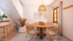 A dining area with a round wooden table, wicker chairs, and a hanging light fixture. - Villa with pool  Pollensa - Can Roig Guillem (Pollensa / Pollença)