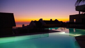 A pool area with a sunset view, overhanging roofs, and a calm water surface.