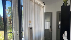 Una sala de estar moderna con un amplio ventanal corredera, una mesa redonda con un adorno y una escultura de cactus.