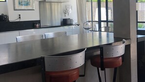 Una cocina moderna con una isla grande, electrodomésticos de acero inoxidable y taburetes de bar.