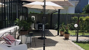 Un patio amueblado con un sofá blanco para exteriores, una mesa y una sombrilla.