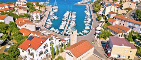 Un puerto deportivo con barcos amarrados, rodeado de edificios residenciales de techos rojos.