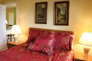 Quarto de hotel com uma cama grande, duas pinturas emolduradas na parede e duas luminárias de cabeceira.