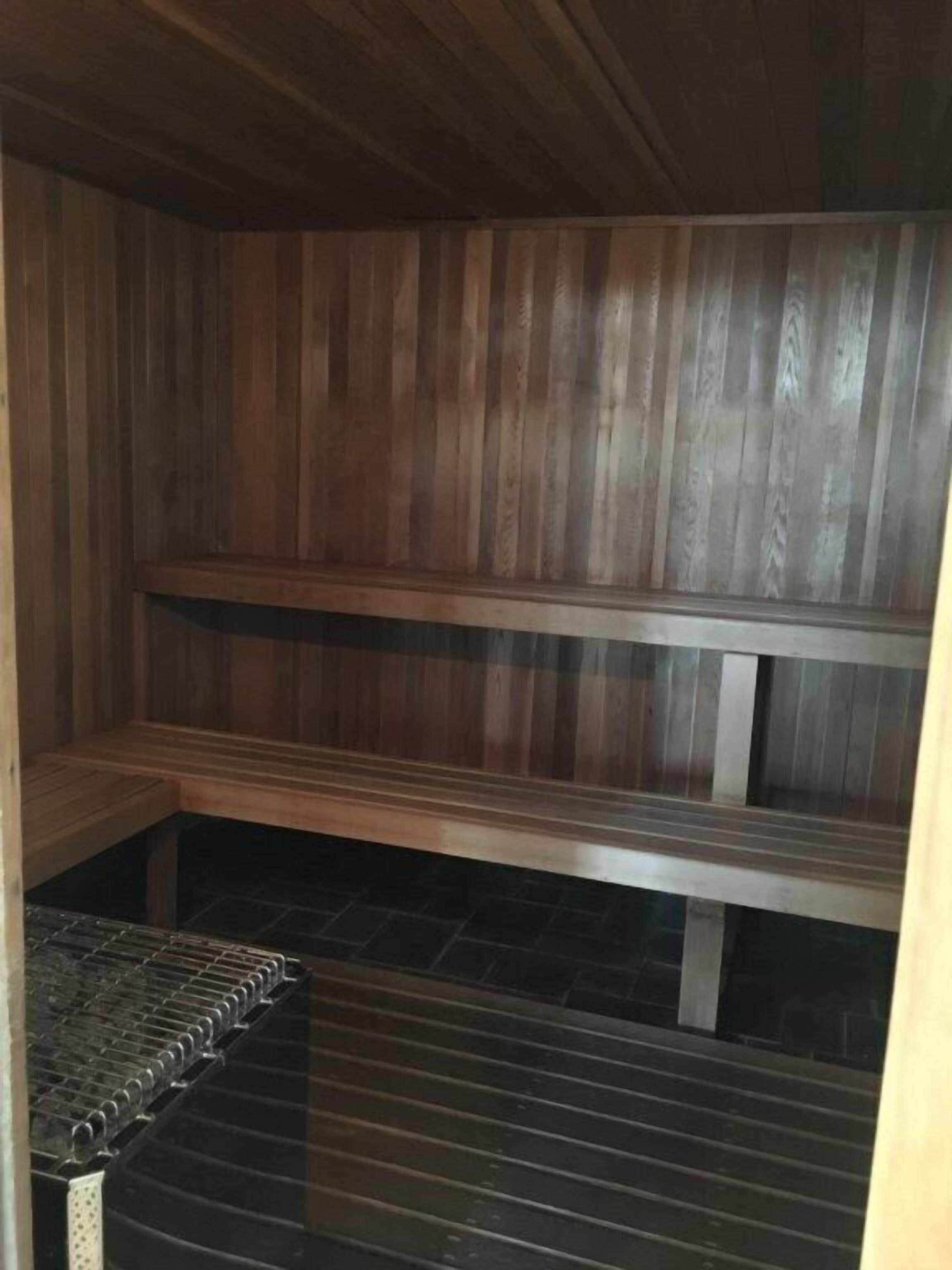 Een sauna met houten banken en een vloer van metalen roosters.