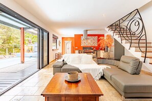Un salon moderne avec un canapé, une table basse et un escalier agrémenté d’une rampe décorative.