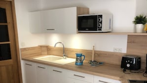 A kitchen with white cabinets, a sink, a microwave, a toaster, and a coffee maker.