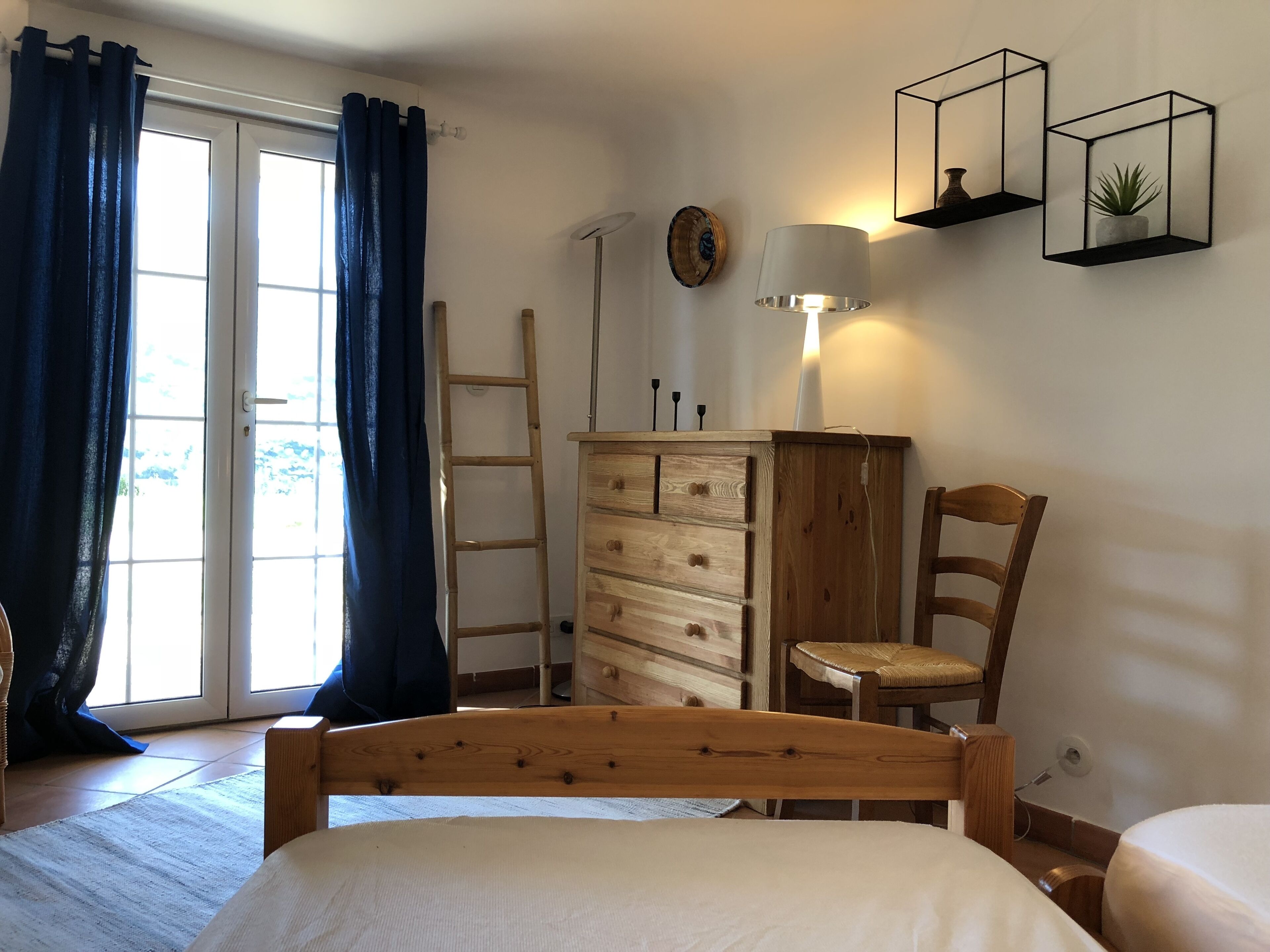 Un dormitorio con cama, cómoda de madera, silla y escritorio con lámpara.