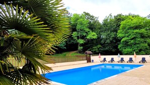 A swimming pool with a tiled deck, surrounded by lush greenery and trees. - Gîte for 5 to 7 people in Sarlat. Heated swimming pool. Wifi. >>Nature (SARLAT LA CANEDA)
