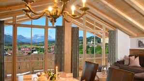 Ein Essbereich mit Tisch, gedeckt für Tee, großen Fenstern mit Bergblick und einer Kristallleuchter.