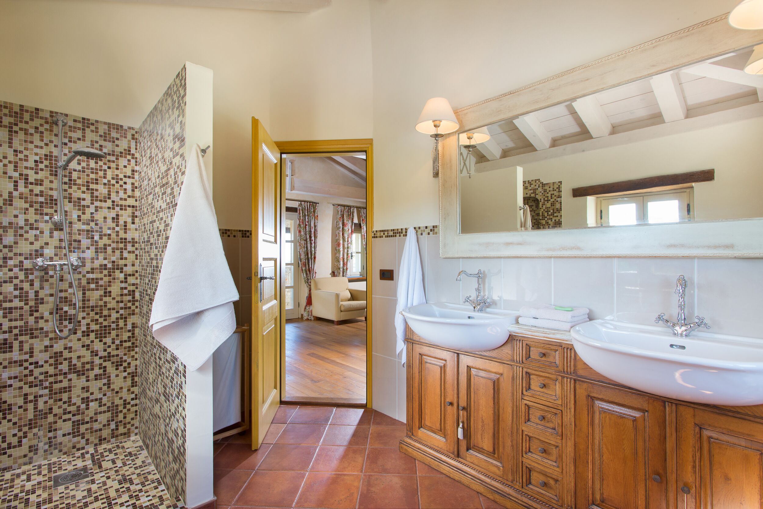 Une salle de bain avec une douche, deux lavabos et un grand miroir.