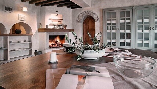 A cozy room with a fireplace, wooden beams, a dining table with a candle, and a large cabinet with glass doors. - First class luxury villa with big pool, 1000sqm living area, 30000 sqm garden (porec)