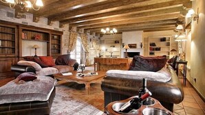A cozy living room with leather sofas, a coffee table, and a fireplace. There are bookshelves and a chandelier. - First class luxury villa with big pool, 1000sqm living area, 30000 sqm garden (porec)