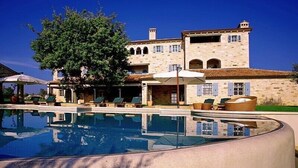 A large building with a swimming pool, outdoor seating, and a tree. - First class luxury villa with big pool, 1000sqm living area, 30000 sqm garden (porec)
