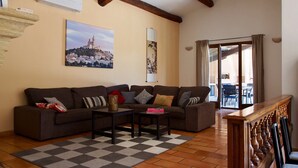 A living room with a brown sofa, a checkered rug, and a wooden railing.