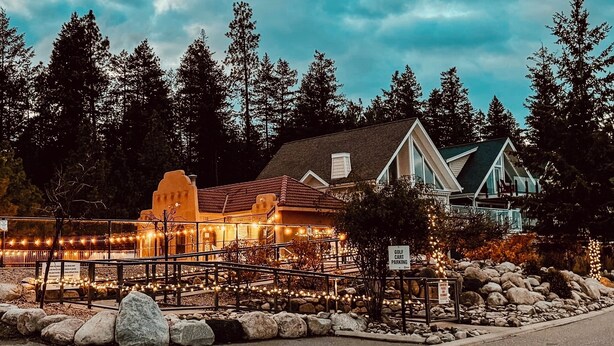 A building with a unique architectural design, surrounded by a stone wall and a wooden fence. - Luxury Modern Lake Cottage, Huge Deck Sleeps 8, Pet Friendly, Close to Amenities (Kelowna)