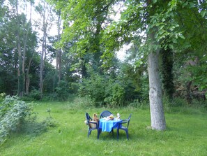 An outdoor dining area with a table set under a tree, surrounded by lush greenery. - Holidays in the center of the biosphere reserve Burg im Spreewald (Burg (Spreewald))