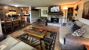 A living room with a fireplace, a television, and a dining area with wooden furniture. - 'Nob Nest' - Perfect location, Close to Everything (Sugar Mountain)