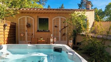 Un bain à remous avec une terrasse en bois, une table avec des chaises et un verre à vin.