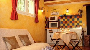 A cozy room with a bed, a dining table with a candle, a book, and a sign on the wall. - Charming cottages, private SPA and private garden (Bédoin)