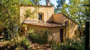 A rustic building with a tiled roof, surrounded by greenery and a stone bench. - Charming cottages, private SPA and private garden (Bédoin)